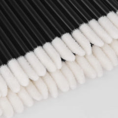 Black lip applicator wands next to lipstick and lip gloss
