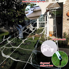 Halloween spider and web decoration displayed over a porch and front yard at night