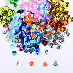 Close-up of mixed multicolor 6mm cup sequins with center holes scattered on white background